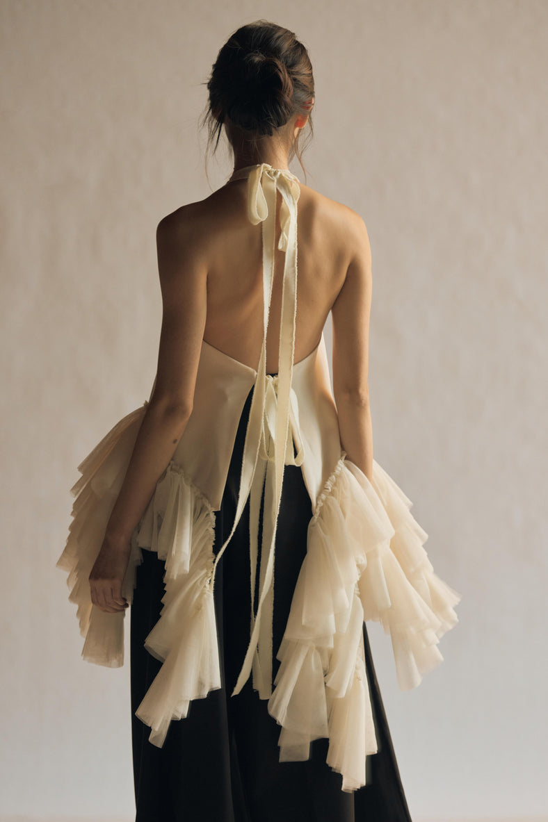  Vania Romoff The Clara Top in ivory features a halter neckline and a relaxed, flowing silhouette in ivory stretch crepe