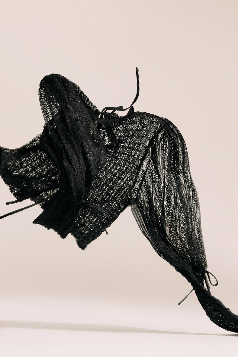 Vania Romoff The Juliet Top in black is crafted from delicate lace and features intricate ruching, a high neckline, and sheer sleeves