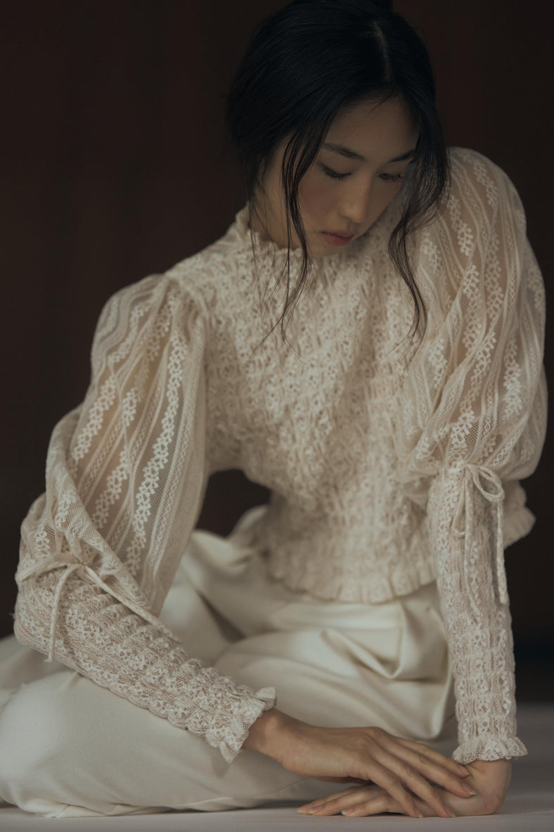 Vania Romoff The Juliet Top in oat is crafted from delicate lace and features intricate ruching, a high neckline, and sheer sleeves