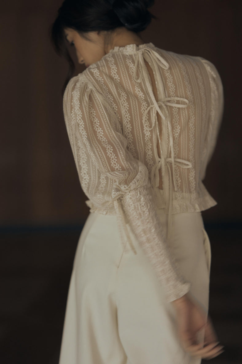 Vania Romoff The Juliet Top in oat is crafted from delicate lace and features intricate ruching, a high neckline, and sheer sleeves